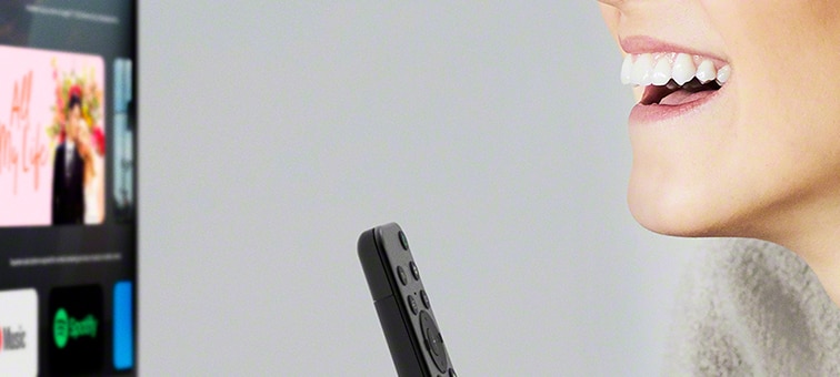 Közelkép a tévéjét hangvezérléssel távolról irányító nőről